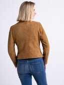 A woman shown from the back wearing a cropped tan suede jacket and blue jeans against a plain white studio background.