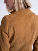 Close-up back view of a model wearing a camel brown suede jacket against a plain white background.