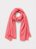 A coral pink scarf with fringed edges, neatly draped and looped in a knot against a clean, light gray background.