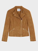 A tan faux-suede motorcycle jacket with gold-tone hardware, featuring an asymmetrical zipper, snap-button collar, and zippered hand pockets, shown against a light gray background.