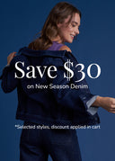 A woman wearing a dark blue denim jacket and matching jeans poses against a solid blue background, with promotional text overlay reading 'Save $30 on New Season Denim'.